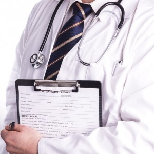 male doctor with stethoscope around his neck, whilst holding a clipboard