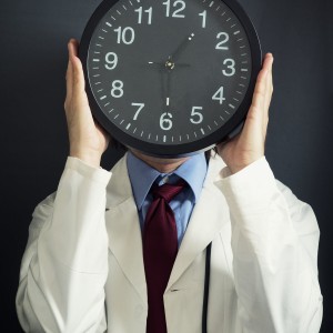 Doctor holding clock in front of face