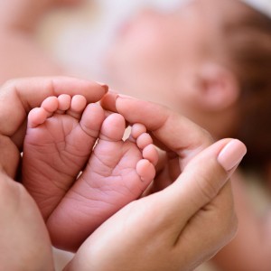 The hands of a midwife holding the delicate feet of a baby