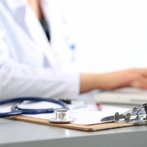 Doctor seated beside professional indemnity insurance forms