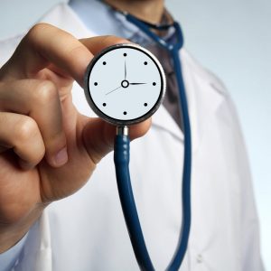 Doctor holding a stethoscope with a clock over its surface