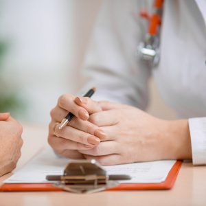 Doctor with folded hands over documentation