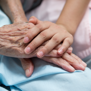 medical professional holding the hand of a patient in palliative care