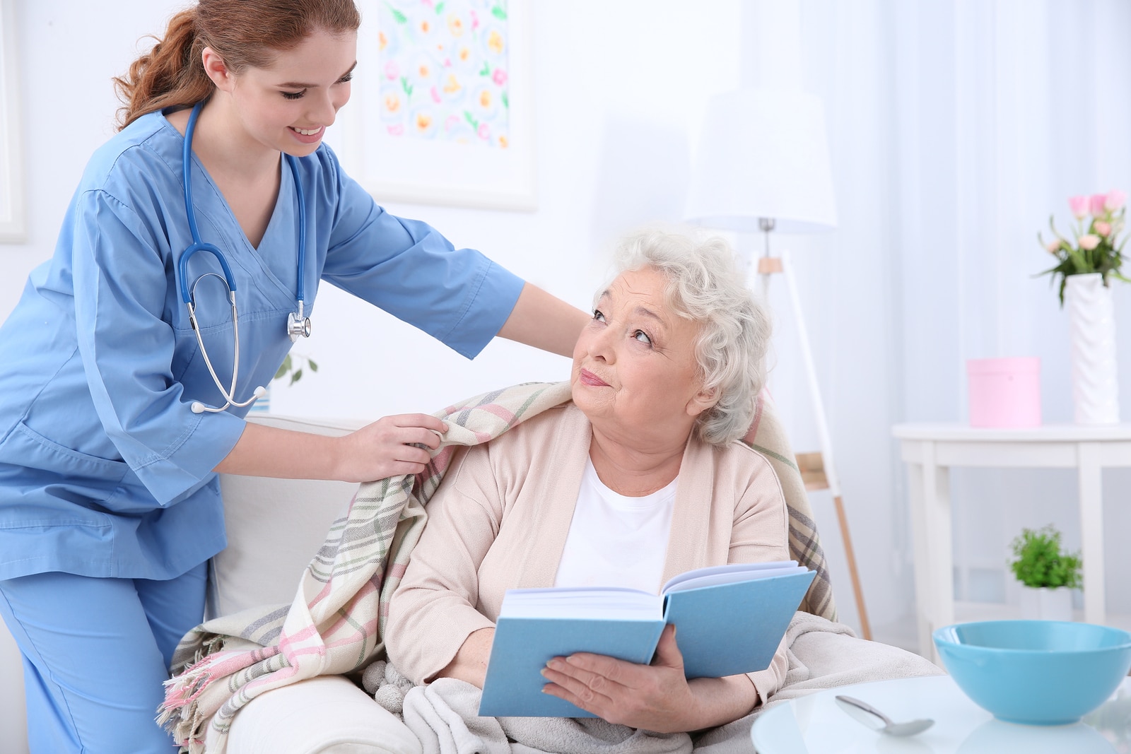 Nurse caring for elderly woman in light room