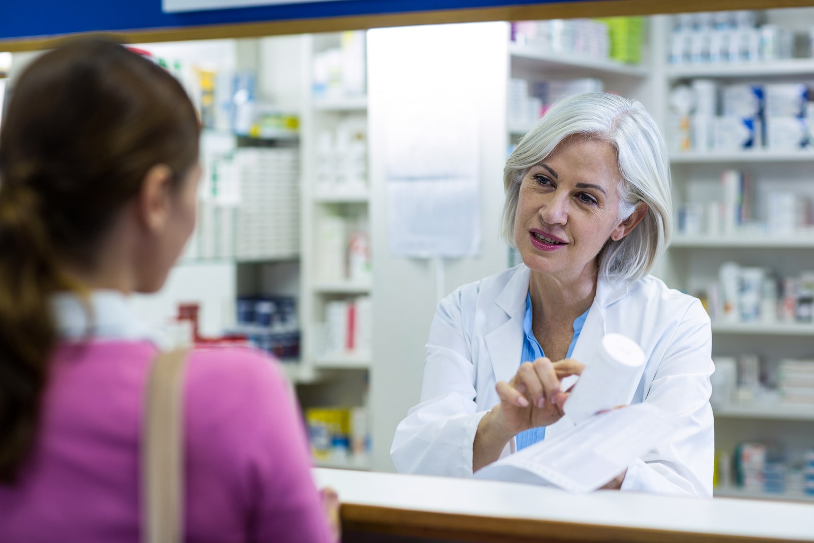 Pharmacist assisting the bottle of painkillers to customer in pharmacy