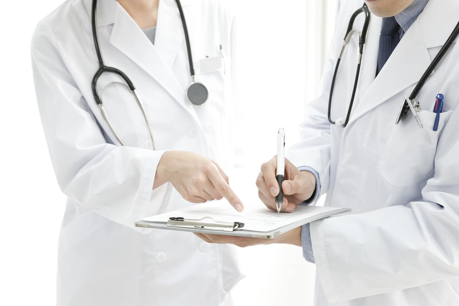 Young team of two doctors with medical stethoscope wearing white medical uniform over white background. Concept of healthcare professional people and medicine