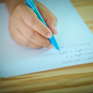 Student testing in exercise exams with blue pen on advanced mathematics (maths) in vintage style.