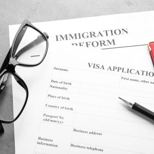 Passports, glasses and visa application form on table. Immigration visa reform