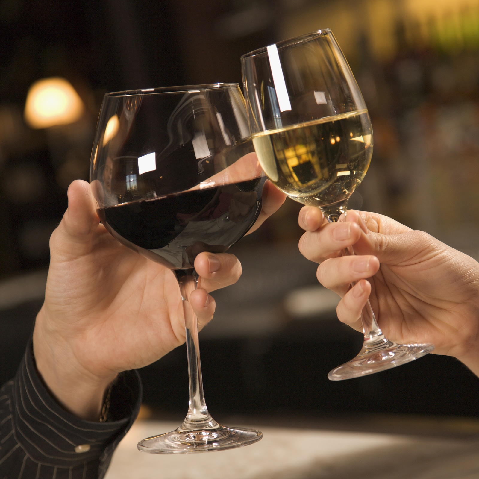 Mid adult Caucasian male and female hands toasting wine glasses.