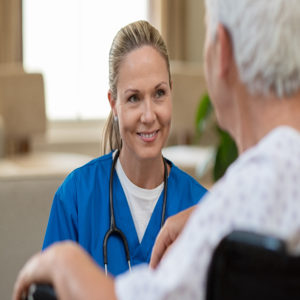 Smiling beautiful nurse in front of patient on wheelchair at hos