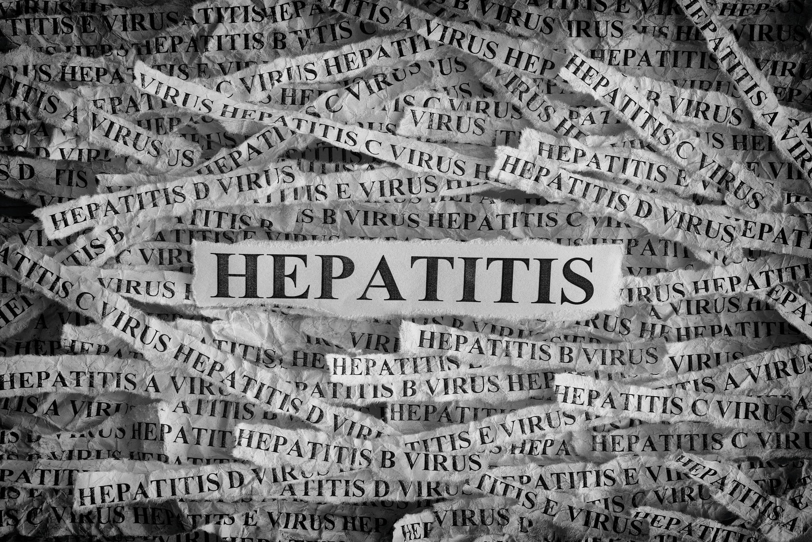  Torn pieces of paper with the words Hepatitis. 