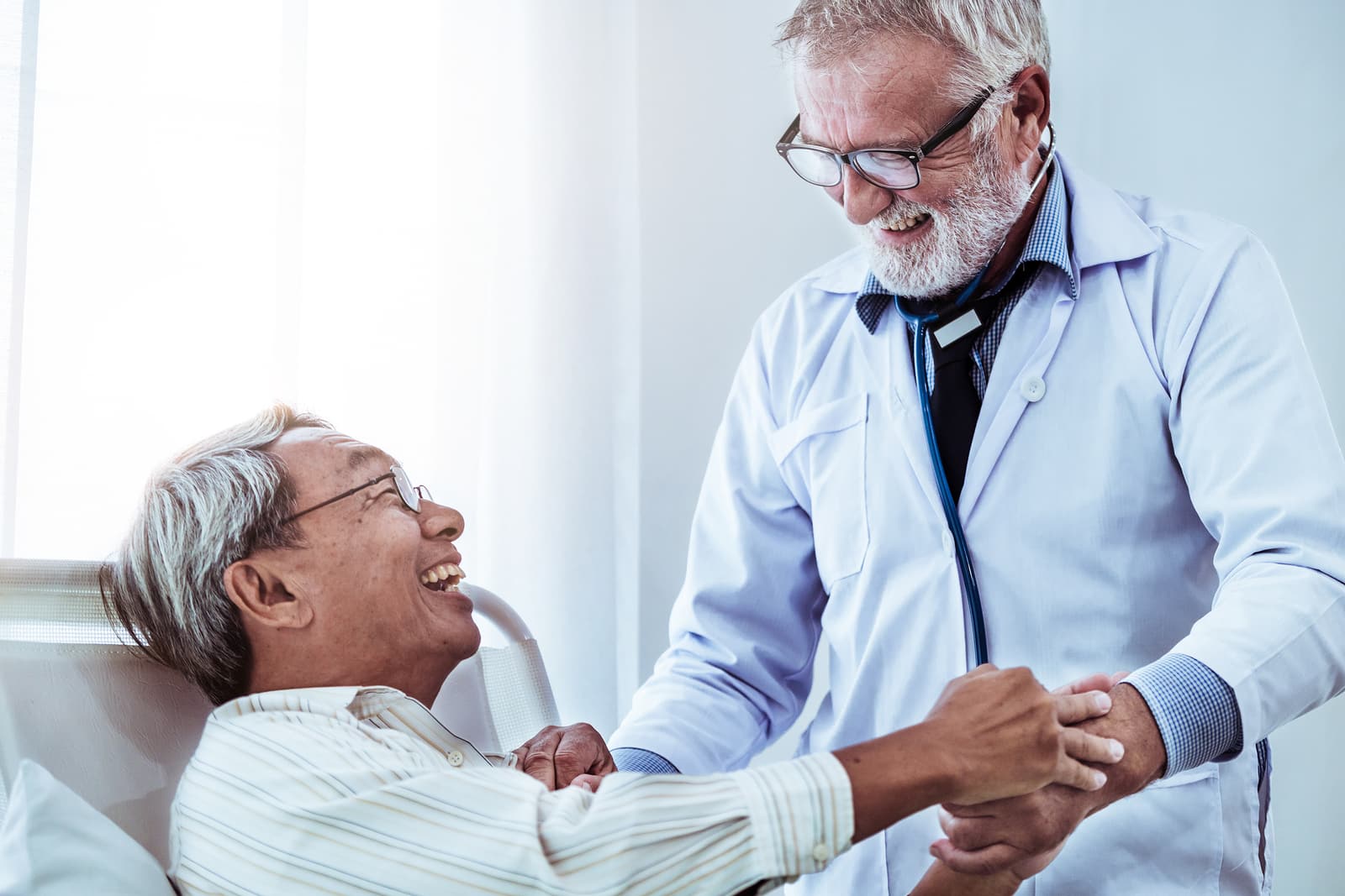 Mature Doctor And Senior Patient In Hospital Ward