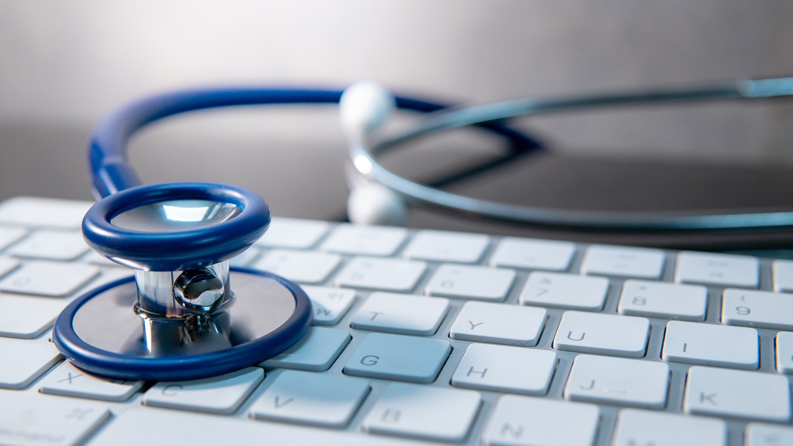 Blue stethoscope on white modern keyboard