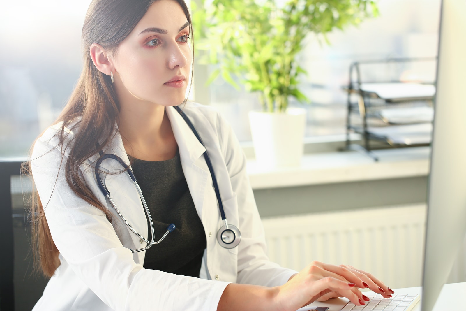 Young Female Doctor Uses Computer In Workplace.